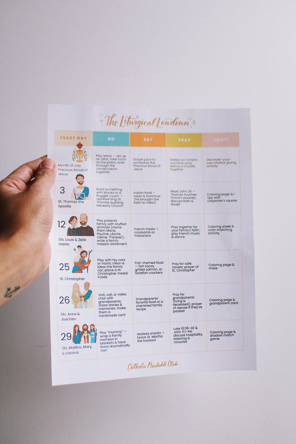 Hand holding a printed sheet with a liturgical calendar on a plain background