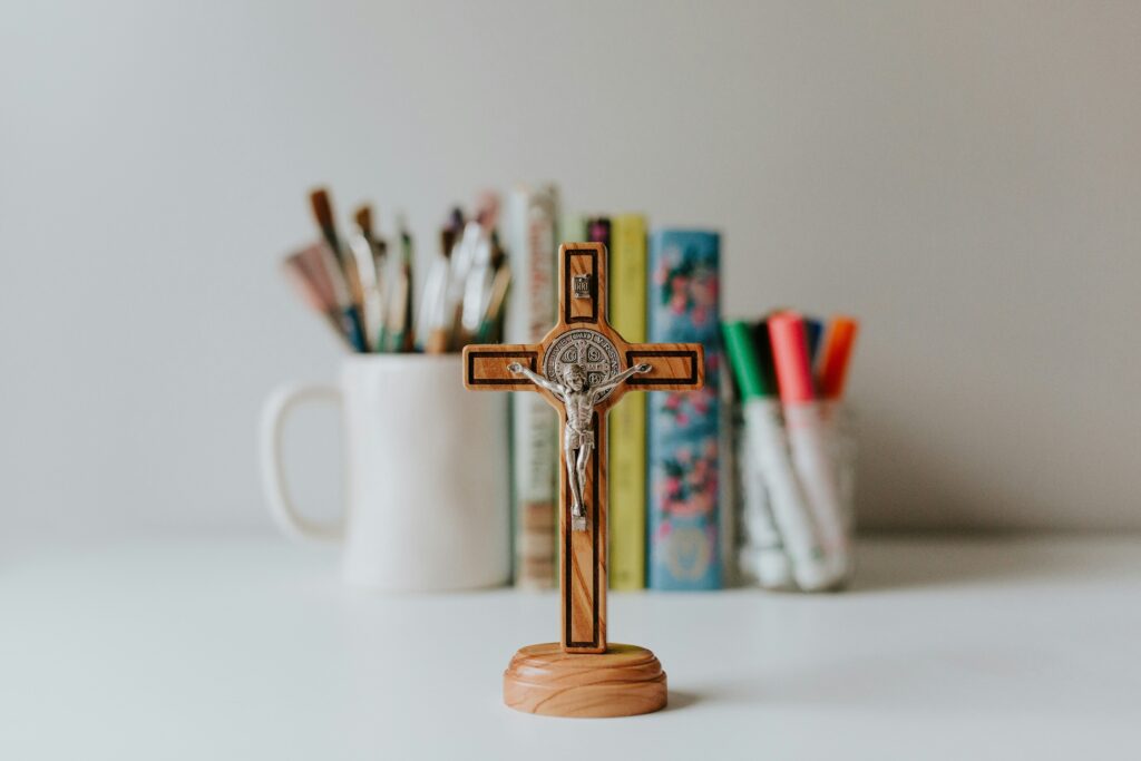 image of crucifix in front of cup of paintbrushes and markers